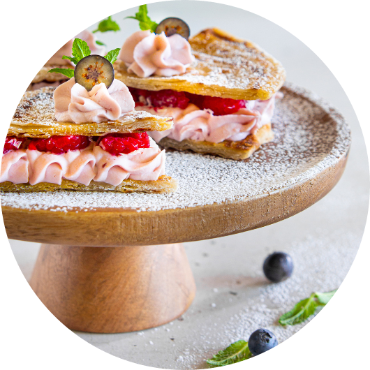 Piadina dolce farcita con crema ai frutti di bosco, lamponi freschi e mirtilli, servita su un'alzata di legno e decorata con zucchero a velo e menta.
