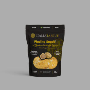 Piadina Snack al Gusto di Tartufo Bianco" prodotta da ITALIA TARTUFI. La confezione è di colore scuro con un design elegante, evidenziando il gusto di tartufo bianco. Il prodotto è descritto come "Bastoncini di piadina fritta croccante" e viene presentato in una confezione da 70g. La confezione include anche informazioni come l'assenza di OGM, la compatibilità vegana e la non presenza di MSG (glutammato monosodico).